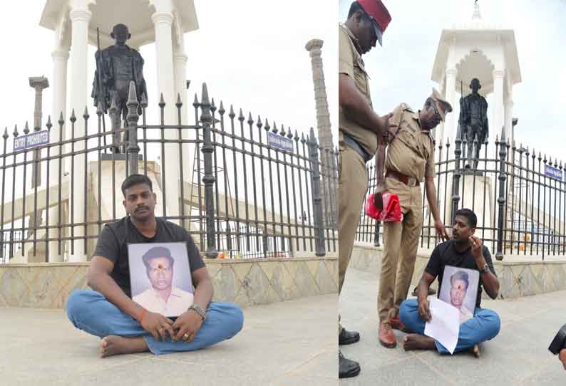 காந்தி சிலை முன் போலீஸ் ஏட்டு மகன் தர்ணா; படத்துடன் அமர்ந்து திடீர் போராட்டம்