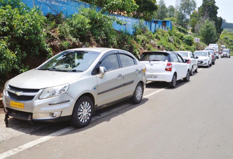 ஊட்டி-கூடலூர் சாலையின் இருபுறங்களிலும், போக்குவரத்துக்கு இடையூறாக நிறுத்தப்படும் வாகனங்கள்